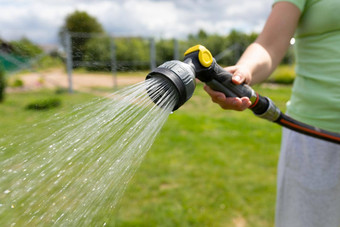 女人浇水草坪上花园软管浇水