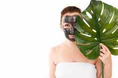 年轻的女人黑色的化妆品面具脸使激活木炭毛巾淋浴白色背景人叶棕榈树手