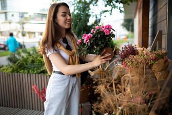 照片欧洲美丽的有吸引力的积极的快乐浅黑肤色的女人女人穿时尚的白色t恤蓝色的牛仔裤选择花礼物街花园摊位小镇街