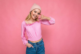 照片美丽的快乐微笑年轻的金发女郎女人孤立的粉红色的背景墙穿时尚的粉红色的他粉红色的上衣相机仿沟通移动电话