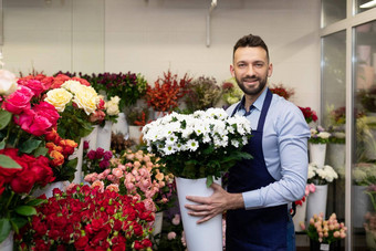 男人。花店冰箱新鲜的花持有花瓶生活植物手相机微笑