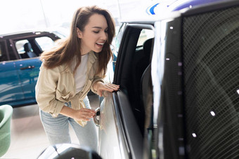 年轻的女人检查<strong>车</strong>经销商购<strong>买车</strong>