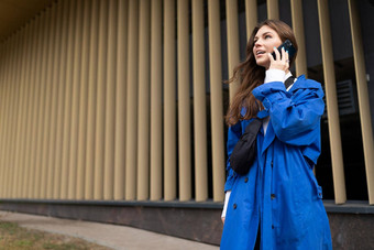 年轻的女人企业家蓝色的外套说话移动电话背景外观购物中心