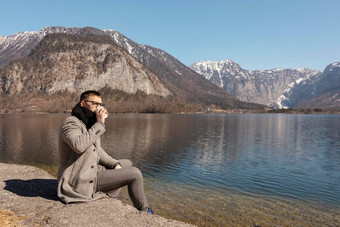 年轻的成人男人。坐着在户外喝咖啡享受山湖好天气蓝色的天空太阳美丽的景观时间做梦放松精神健康假期