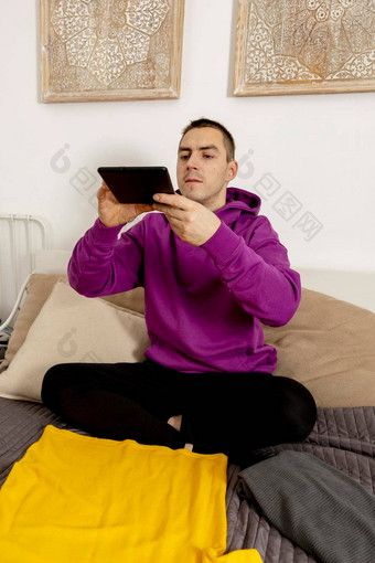 男人。紫罗兰色的连帽衫数字平板电脑需要照片衣服出售在线销售网站电子商务重用二手概念有意识的消费者可持续发展的生活方式