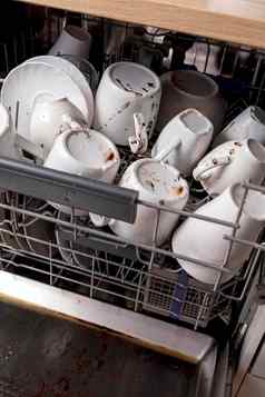 未洗的脏菜洗碗机混乱厨房脏厨房用具盘子杯子混乱的餐具关闭视图