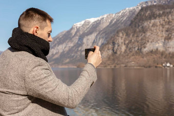 年轻的成人男人。采取图片智能手机享受山湖好天气蓝色的天空太阳美丽的令人惊异的景观旅游假期假期旅行时间旅游使照片
