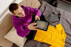 男人。紫罗兰色的连帽衫数字平板电脑需要照片衣服出售在线销售网站电子商务重用二手概念有意识的消费者可持续发展的生活方式