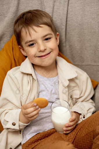 可爱的男孩坐着沙发上首页喝<strong>牛奶</strong>饼干新鲜的<strong>牛奶</strong>玻璃乳制品健康的喝医疗保健源<strong>钙</strong>乳糖学前教育孩子休闲服装
