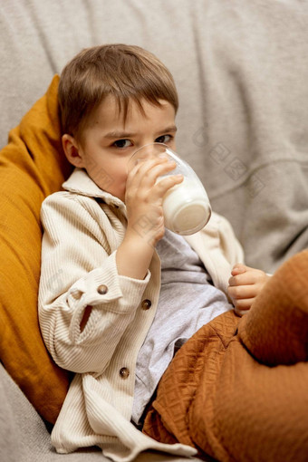 可爱的男孩坐着沙发上首页喝牛奶新鲜的牛奶玻璃乳制品健康的喝医疗保健源钙乳糖学前教育孩子休闲服装