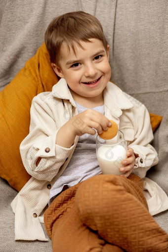 可爱的男孩坐着沙发上首页喝牛奶饼干新鲜的牛奶玻璃乳制品健康的喝医疗保健源钙乳糖学前教育孩子休闲服装