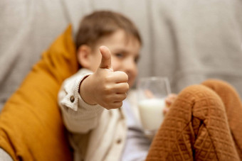 可爱的男孩坐着沙发上首页喝牛奶新鲜的牛奶玻璃乳制品健康的喝医疗保健源钙乳糖学前教育孩子休闲服装拇指