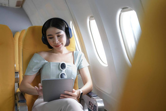 旅行旅游现代技术空气航班概念女人坐着飞机现代数字小工具<strong>搜索</strong>最喜欢的音乐播放<strong>列表</strong>应用程序听