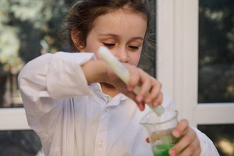 淘气的学前教育女孩进行化学实验倒液体测试管实验室瓶学习化学科学类