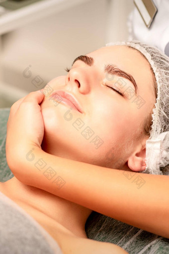 面部按摩手按摩师按摩脖子年轻的高加索人女人水疗中心沙龙概念健康按摩