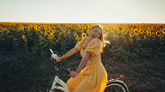 农村女人永恒的衣服骑复古的风格白色自行车国家路向日葵场古董时尚令人惊异的冒险农村活动健康的生活方式