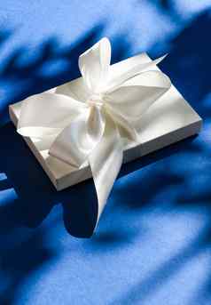 奢侈品假期白色礼物盒子丝绸丝带弓蓝色的背景奢侈品婚礼生日现在