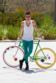 样式环保英俊的年轻的男人。骑自行车在户外
