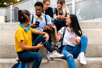 快乐多民族的十几岁的高学校学生坐步骤会说话的<strong>移动手机</strong>