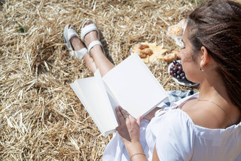 年轻的女人白色衣服坐着干草堆收获场阅读空白书书模型