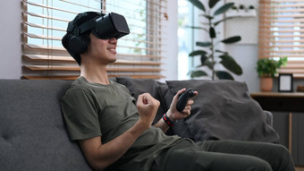 快乐的亚洲男人。穿虚拟现实耳机玩模拟拳击游戏生活房间未来技术概念