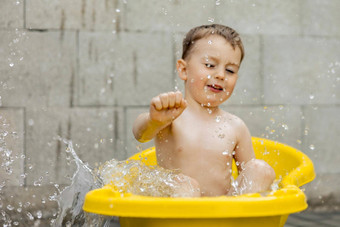 可爱的男孩洗澡黄色的浴缸在户外快乐孩子溅玩水有趣的<strong>夏天季</strong>节娱乐住很酷的<strong>夏天</strong>热水有趣的后院