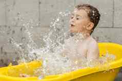 可爱的男孩洗澡黄色的浴缸在户外快乐孩子溅玩水有趣的夏天季节娱乐住很酷的夏天热水有趣的后院