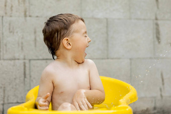 可爱的男孩洗澡黄色的<strong>浴缸</strong>在户外快乐孩子溅玩水有趣的夏天季节娱乐住很酷的夏天<strong>热水</strong>有趣的后院