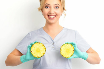年轻的高加索人微笑女人医生<strong>营养学家</strong>持有片菠萝孤立的白色背景乳房健康概念