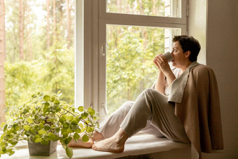 中间年龄美丽的女人坐着窗台上喝茶做梦岁的女人放松杯茶放松首页思考压力免费的和平情绪幸福