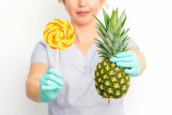 年轻的高加索人女医生<strong>营养学家</strong>持有新鲜的菠萝棒棒糖白色背景