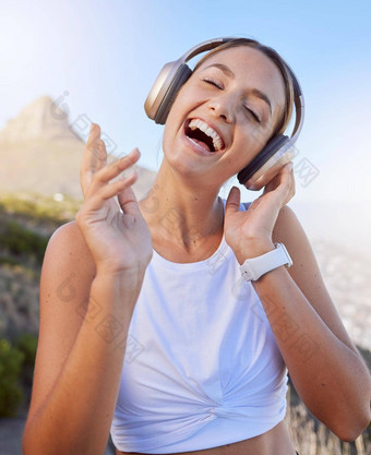 健身耳机女人户外听音乐健康播客培训锻炼锻炼蓝色的天空镜头耀斑年轻的人音频锻炼山
