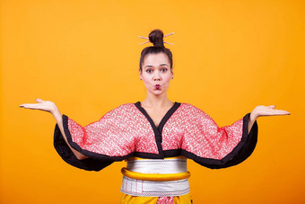 美丽的年轻的女人穿日本服装黄色的背景