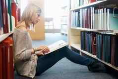 研究最后考试年轻的女人坐着地板上阅读图书馆