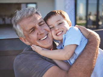 快乐微笑祖父拥抱孙子玩家庭首页幸福好玩的上了年纪的男人。退休拥抱成键蹒跚学步的孙子
