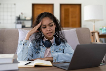 疲惫非裔美国人女商人头疼办公室无聊年轻的非洲女孩累了学习坐首页移动PC冷漠的黑色的女大学学生沮丧