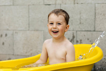 可爱的男孩洗澡黄色的浴缸在户外快乐孩子溅玩水有趣的<strong>夏天季</strong>节娱乐住很酷的<strong>夏天</strong>热水有趣的后院