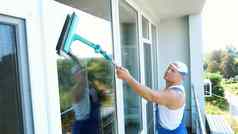高加索人英俊的男人。工人清洁服务蓝色的工作服帽巴索清洁洗窗户特殊的拖把享受工作