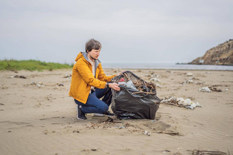 塑料垃圾海海洋污染海滩清洁年轻的男人。挑选塑料瓶沙子海岸环境积极分子收集垃圾保存地球自然保护