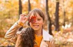 关闭肖像女孩涵盖了眼睛枫木秋天叶秋天季节孩子们概念