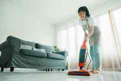 年轻的女人清洁房子真空更清洁的