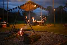 篝火野营帐篷在户外人坐着背景晚上