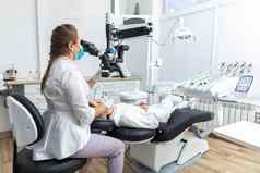 女牙医牙科显微镜治疗病人牙齿牙科诊所办公室