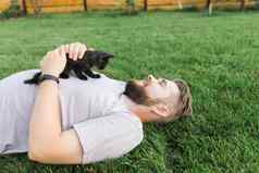 男人。小猫说谎玩草友谊爱动物宠物老板概念