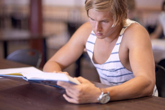 研究努力即将到来的考试年轻的男人。研究考试图书馆