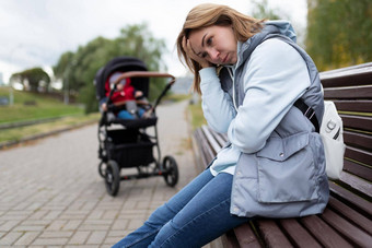 年轻的女人妈妈。产后抑郁症坐在内置的感情公园板凳上婴儿巡回演出的演员