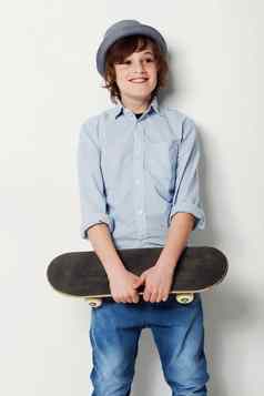 潮流引领者轮子可爱的13岁以下的男孩穿时尚的服装持有滑板孤立的白色