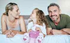 快乐微笑家庭放松床上成键平静舒适的卧室幸福爱护理父母女孩孩子持有泰迪休息现代首页