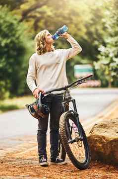 健康骑自行车女人喝水打破自然水合物健康休息在户外体育锻炼渴了骑摩托车的人骑自行车路让人耳目一新液体