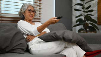 中间岁的女人看舒适的沙发享受无忧无虑的休闲周末活动首页